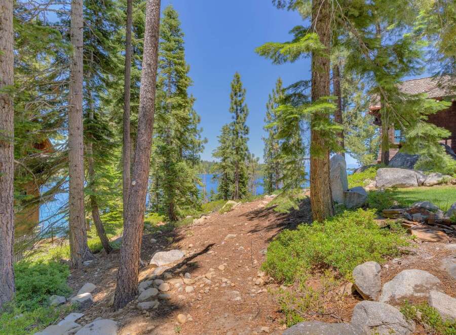 Discover a serene lakeside retreat nestled amongst towering pine trees, offering breathtaking views of the sparkling blue water.