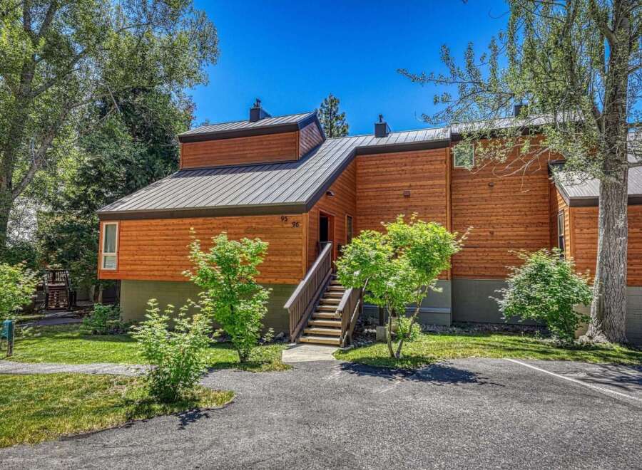 Experience modern mountain living in this stunning wood-clad property featuring a sleek metal roof and a welcoming entrance with a wooden staircase.