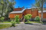 Experience modern mountain living in this stunning wood-clad property featuring a sleek metal roof and a welcoming entrance with a wooden staircase.