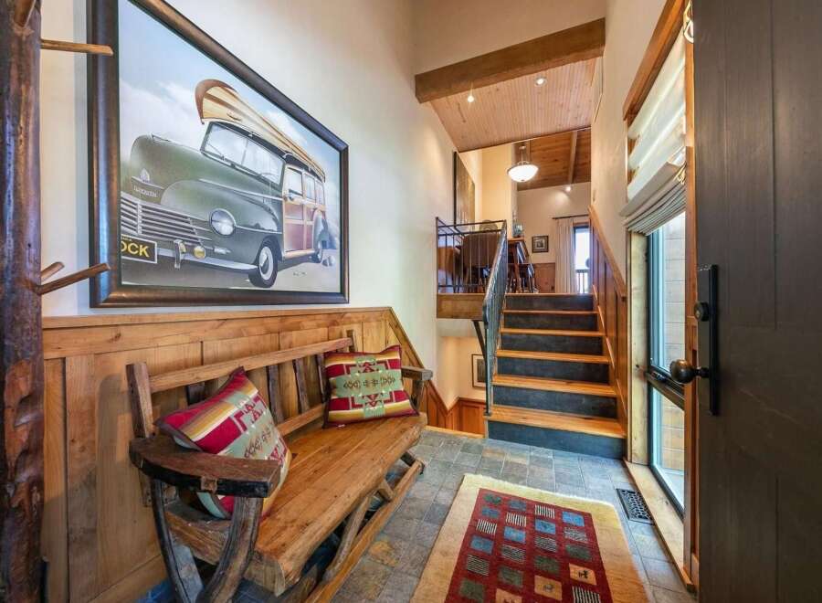 Step into this charming entryway featuring a rustic wooden bench adorned with decorative pillows, perfect for a cozy welcome.