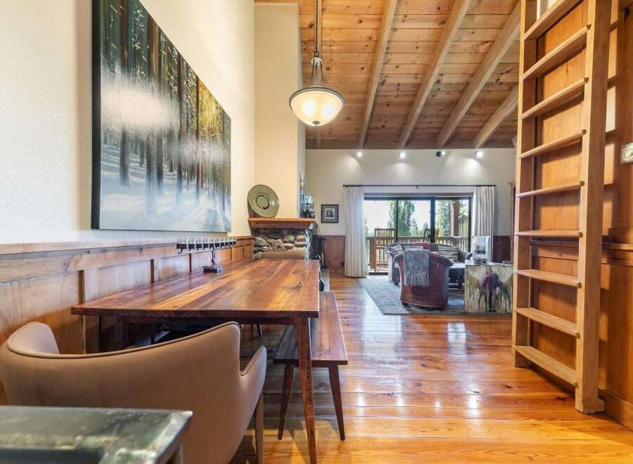 Experience rustic charm in this spacious dining and living area, featuring a large wooden dining table perfect for gatherings.