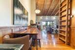 Experience rustic charm in this spacious dining and living area, featuring a large wooden dining table perfect for gatherings.