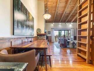 Experience rustic charm in this spacious dining and living area, featuring a large wooden dining table perfect for gatherings.