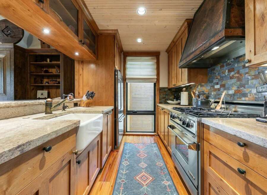 Experience rustic charm in this beautifully appointed kitchen, featuring warm wood cabinetry and a farmhouse sink.