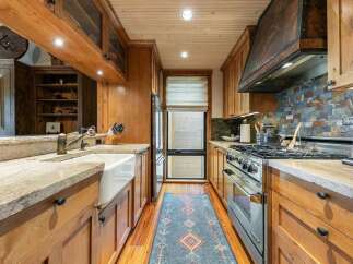 Experience rustic charm in this beautifully appointed kitchen, featuring warm wood cabinetry and a farmhouse sink.