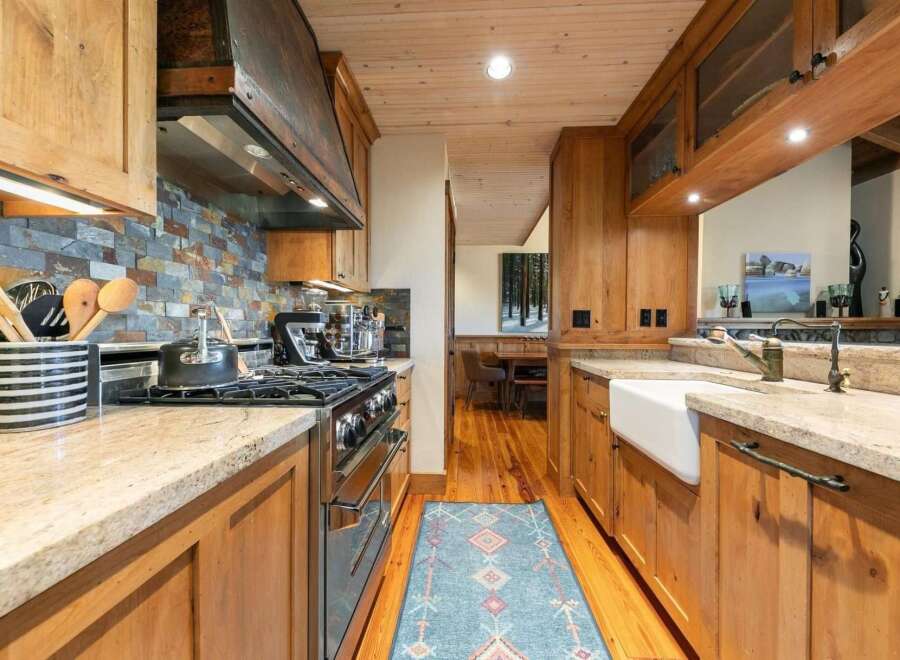 Experience rustic charm in this beautifully appointed kitchen, featuring warm wooden cabinetry and a striking stacked stone backsplash.
