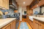 Experience rustic charm in this beautifully appointed kitchen, featuring warm wooden cabinetry and a striking stacked stone backsplash.