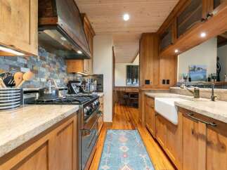 Experience rustic charm in this beautifully appointed kitchen, featuring warm wooden cabinetry and a striking stacked stone backsplash.