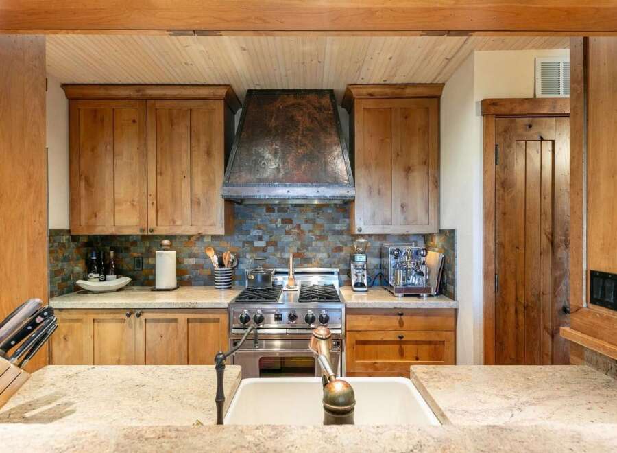Experience rustic charm in this beautifully appointed kitchen, featuring custom wood cabinetry and a striking copper range hood.