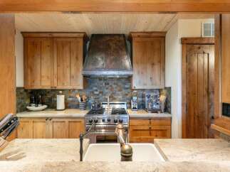 Experience rustic charm in this beautifully appointed kitchen, featuring custom wood cabinetry and a striking copper range hood.