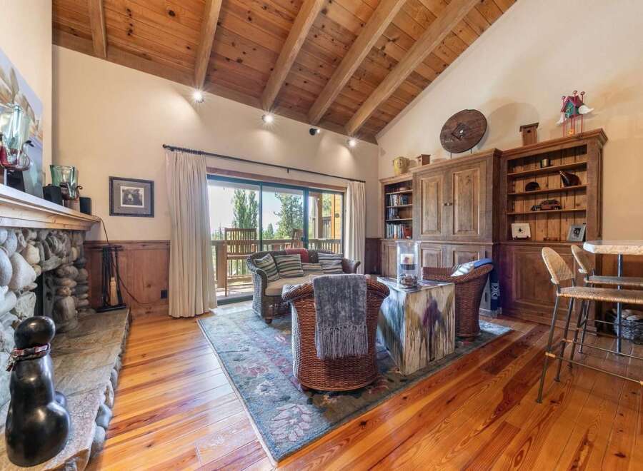 Experience rustic charm in this inviting living room, featuring a magnificent stone fireplace and a vaulted wood-beamed ceiling.