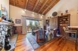Experience rustic charm in this inviting living room, featuring a magnificent stone fireplace and a vaulted wood-beamed ceiling.