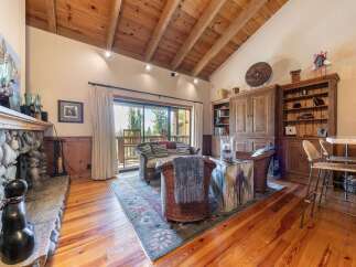 Experience rustic charm in this inviting living room, featuring a magnificent stone fireplace and a vaulted wood-beamed ceiling.
