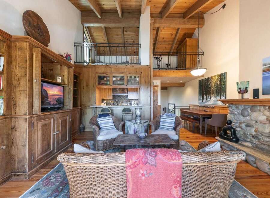 Experience rustic charm and spacious living in this stunning mountain home, featuring a grand stone fireplace and a soaring wood-beamed ceiling.