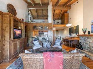 Experience rustic charm and spacious living in this stunning mountain home, featuring a grand stone fireplace and a soaring wood-beamed ceiling.