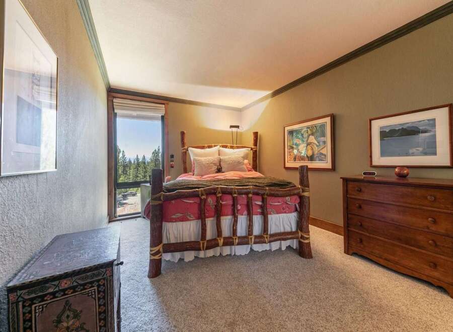 Experience rustic charm in this cozy bedroom, featuring a unique log bed and a picturesque window with stunning forest views.