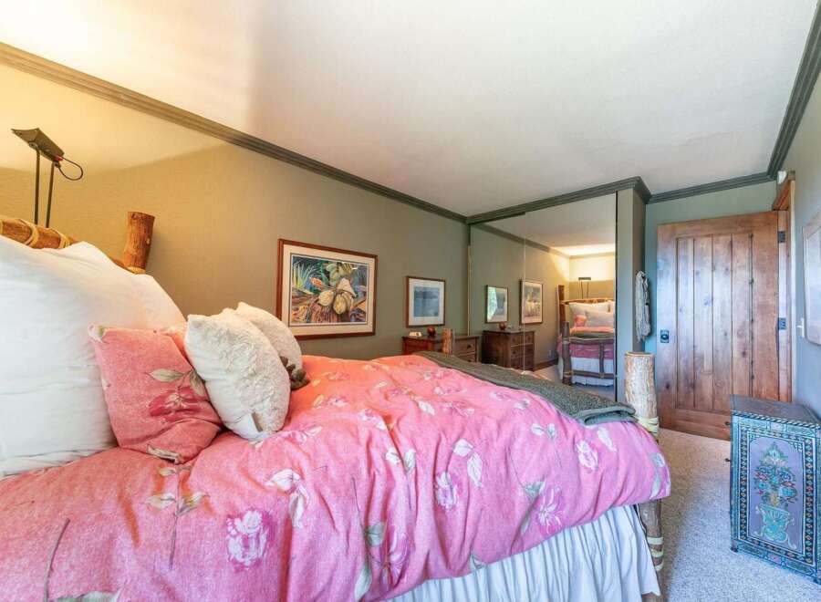 This charming bedroom features a cozy queen-size bed adorned with a vibrant pink floral comforter and plush pillows.