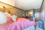 This charming bedroom features a cozy queen-size bed adorned with a vibrant pink floral comforter and plush pillows.