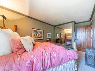 This charming bedroom features a cozy queen-size bed adorned with a vibrant pink floral comforter and plush pillows.