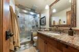Experience rustic elegance in this beautifully appointed bathroom, featuring a spacious walk-in shower with intricate tile work and dual shower heads.