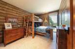 Experience rustic charm in this cozy cabin-style bedroom, featuring a sturdy log bunk bed perfect for family or guests.