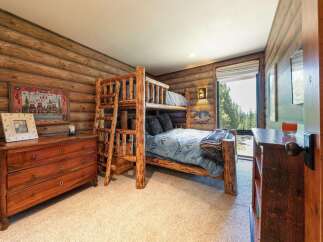 Experience rustic charm in this cozy cabin-style bedroom, featuring a sturdy log bunk bed perfect for family or guests.