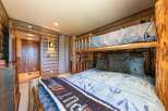 Experience rustic charm in this unique bedroom featuring a log bunk bed and cozy wood-paneled walls.