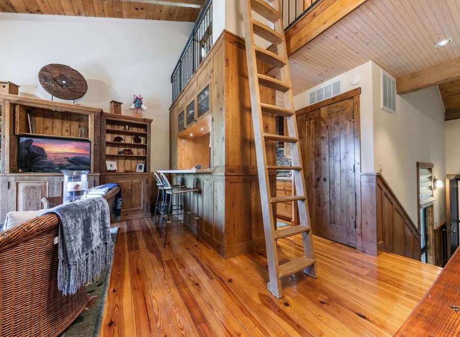 Experience rustic charm in this inviting living space featuring a prominent wooden ladder leading to a loft area.