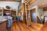 Experience rustic charm in this inviting living space featuring a prominent wooden ladder leading to a loft area.