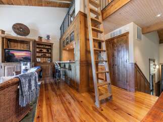 Experience rustic charm in this inviting living space featuring a prominent wooden ladder leading to a loft area.