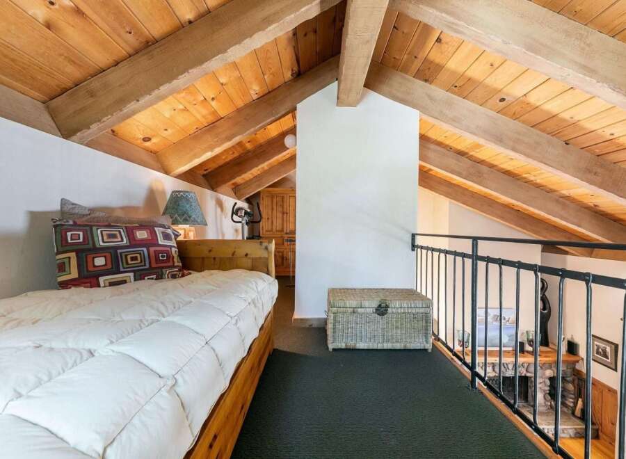 Discover this charming loft bedroom featuring a cozy bed with a decorative pillow and a rustic wooden headboard.