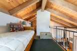 Discover this charming loft bedroom featuring a cozy bed with a decorative pillow and a rustic wooden headboard.