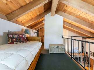 Discover this charming loft bedroom featuring a cozy bed with a decorative pillow and a rustic wooden headboard.