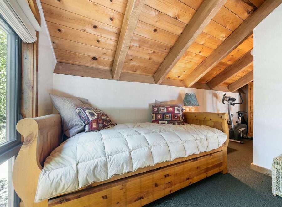 Discover cozy living in this charming bedroom featuring a rustic wooden daybed adorned with plush pillows and a quilted comforter.