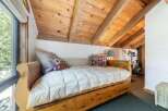 Discover cozy living in this charming bedroom featuring a rustic wooden daybed adorned with plush pillows and a quilted comforter.