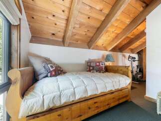 Discover cozy living in this charming bedroom featuring a rustic wooden daybed adorned with plush pillows and a quilted comforter.