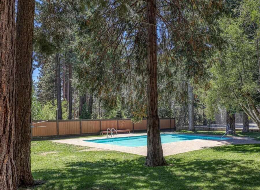 Enjoy a refreshing dip in this sparkling blue swimming pool, surrounded by lush green grass and mature trees.