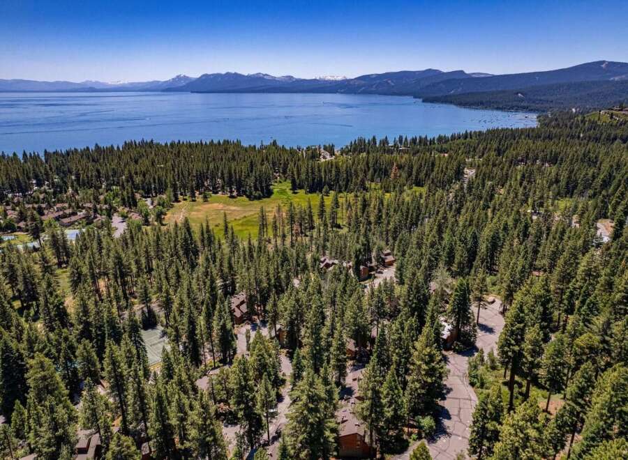Experience the ultimate mountain lifestyle with this stunning aerial view of a property nestled amidst a dense pine forest.