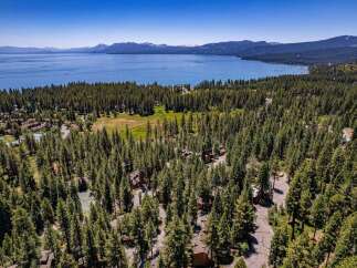 Experience the ultimate mountain lifestyle with this stunning aerial view of a property nestled amidst a dense pine forest.