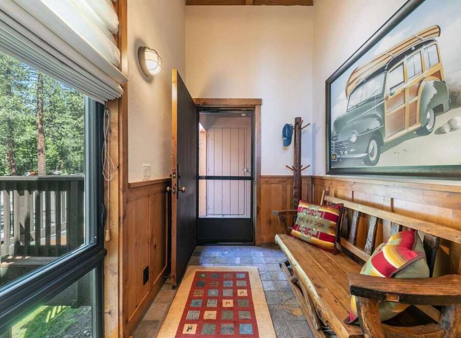 Step into this charming entryway featuring rustic wood paneling and a cozy bench perfect for removing shoes.