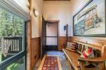 Step into this charming entryway featuring rustic wood paneling and a cozy bench perfect for removing shoes.