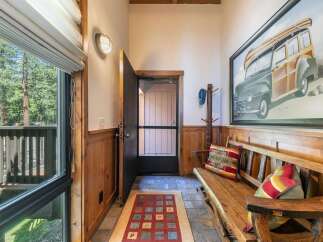 Step into this charming entryway featuring rustic wood paneling and a cozy bench perfect for removing shoes.