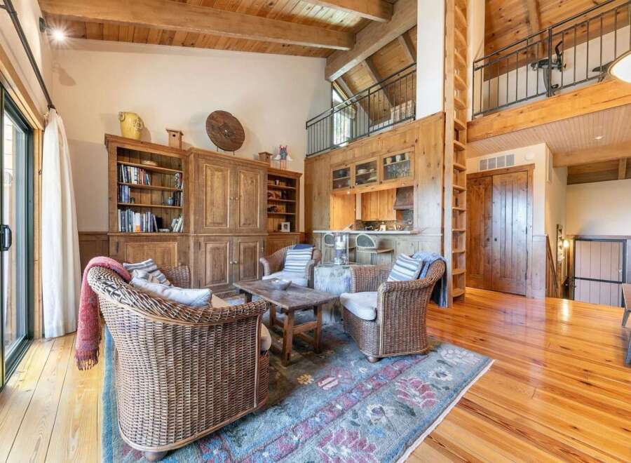 Experience rustic charm in this spacious living area featuring a cozy seating arrangement with wicker chairs and a rustic wooden coffee table.