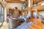 Experience rustic charm in this spacious living area featuring a cozy seating arrangement with wicker chairs and a rustic wooden coffee table.