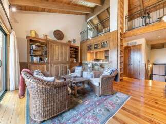 Experience rustic charm in this spacious living area featuring a cozy seating arrangement with wicker chairs and a rustic wooden coffee table.