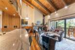 Experience rustic charm in this inviting living space featuring a stunning stone fireplace and a vaulted wood-beamed ceiling.
