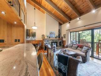 Experience rustic charm in this inviting living space featuring a stunning stone fireplace and a vaulted wood-beamed ceiling.