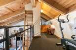 Ascend to this charming loft space, featuring exposed wooden beams and a rustic ladder leading to an upper level.