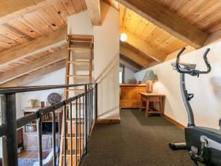 Ascend to this charming loft space, featuring exposed wooden beams and a rustic ladder leading to an upper level.