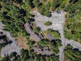 Discover this stunning aerial view showcasing a cluster of modern townhomes nestled amidst a dense forest.